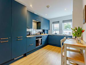 a kitchen with blue cabinets and a wooden table at 2 Bed in Sandown oc-89291 in Sandown