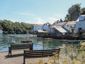 a bench sitting next to a river with houses and boats at Fairways 4 in Liskeard