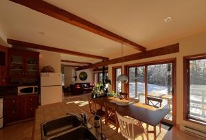 a kitchen and living room with a table and chairs at Le Domek de nature apaisante in Sainte Béatrix