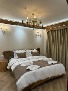 a bedroom with a large bed with a chandelier at Hotel Restorant Unaza in Voskopojë