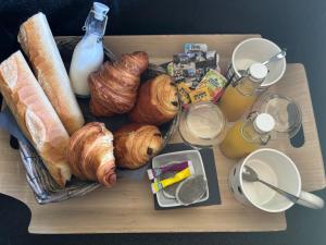 a tray with bread and croissants and drinks on a table at Le Podium in Cappellebrouck