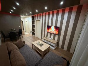 a living room with a couch and a tv on a wall at Perisic Apartman Obrenovac, sa parkingom in Obrenovac
