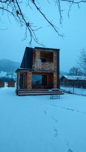 a building with a bench in the snow at Tiny Marae in Straja