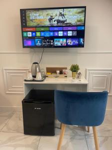 a desk with a blue chair and a tv on the wall at DOMUS LUIGI LEONE 2 in Naples