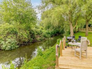 a wooden deck with a table and chairs next to a river at 1 Bed in Wareham oc-88099 in Wool