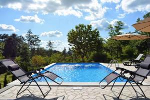 a swimming pool with two chairs and an umbrella at Vikendica Popovic in Doboj