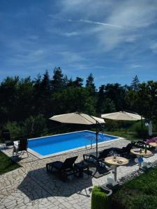 a swimming pool with umbrellas and chairs and tables at Vikendica Popovic in Doboj