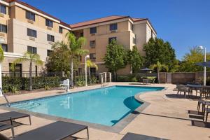 a swimming pool with tables and chairs in front of a building at Courtyard by Marriott Sacramento Midtown in Sacramento