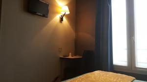 um quarto com uma cama e um candeeiro na parede em Café Hôtel de l'Avenir em Saint-Ouen