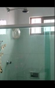 a bathroom with a glass shower with a window at Casa na várzea Quarto 1 in Recife