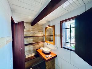 a bathroom with a sink and a mirror and a window at Pousada e Restaurante do Paulo in Jijoca de Jericoacoara