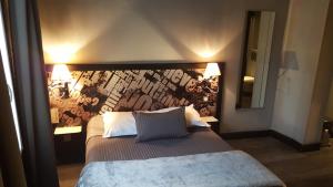a bedroom with a large bed with a wall at Café Hôtel de l'Avenir in Saint-Ouen