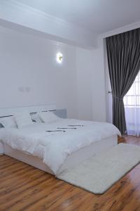 a white bed in a bedroom with a large window at Abat property Rental in Addis Ababa