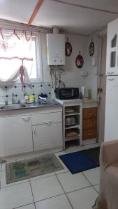 a kitchen with white cabinets and a sink and a window at Cabaña El Quijote in Valdivia