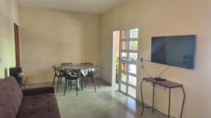 a living room with a table and chairs and a flat screen tv at Chácara Anna Julia in Piedade