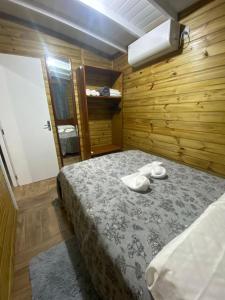 a bedroom with a bed in a wooden room at Conforto na praia 2 Quartos com Ar Até 6 Pessoas in Imbituba