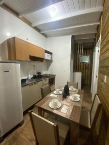 a kitchen with a table with chairs and a refrigerator at Conforto na praia 2 Quartos com Ar Até 6 Pessoas in Imbituba