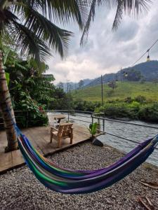a hammock with a table and a bench on a deck at Yaxlik River Lodge in Lanquín