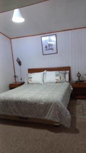 a bedroom with a bed with two night stands and two lamps at Cabaña El Quijote in Valdivia