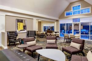 a waiting room with chairs and tables and windows at Residence Inn Worcester in Worcester