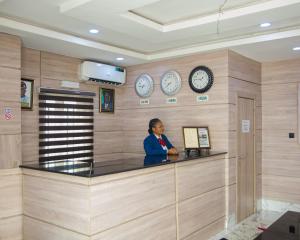 a woman standing at a counter with clocks on the wall at Golden Tulip Hotel in Asaba +53 photos
