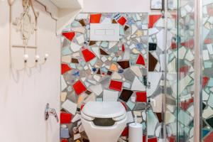 a bathroom with a toilet and a mosaic wall at La Locanda di Diogene in Case Reggiani