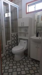 a white bathroom with a toilet and a sink at Cabaña El Quijote in Valdivia