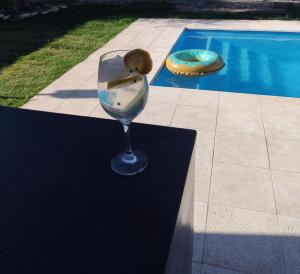 a wine glass sitting on a table next to a swimming pool at Complejo Los Olivos in Ciudad Lujan de Cuyo