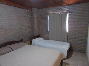 a bedroom with two beds and a brick wall at Complejo Kallpa in Santiago del Estero