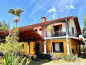 a yellow and white house with a palm tree at Hotel Honey Bee in Alajuela
