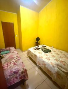 a bedroom with two beds and yellow walls at hospedagem de ze maninha in Lençóis +9 photos