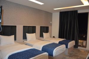 a hotel room with three beds and a window at MyFlower 3 Hotel in Erbil +62 photos