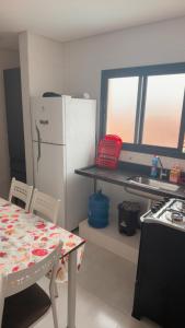 a kitchen with a table and a white refrigerator at Casa 3 dormitórios 100 metros da praia in Praia Grande