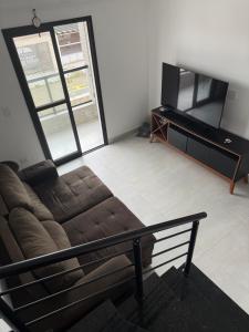 a living room with a couch and a flat screen tv at Casa 3 dormitórios 100 metros da praia in Praia Grande