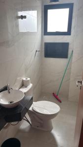 a white bathroom with a toilet and a sink at Casa 3 dormitórios 100 metros da praia in Praia Grande +10 photos