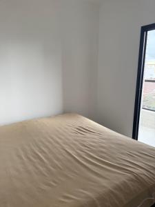 a bed in a white room with a window at Casa 3 dormitórios 100 metros da praia in Praia Grande