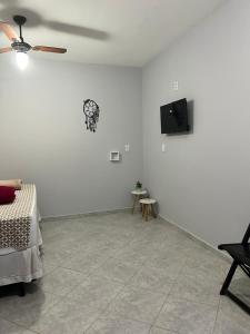 a white room with a bed and a tv on a wall at Pousada Cantinho da Jú in Pirenópolis