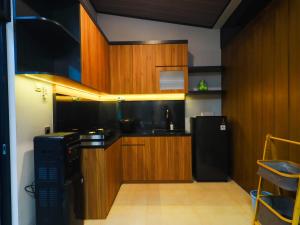 a kitchen with wooden cabinets and a black refrigerator at Pickle n Pod villa in Solo with pickle court near mall in Grogol +9 photos