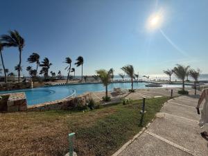 a swimming pool next to a beach with palm trees at Departamento Playa Punta Diamante in Acapulco