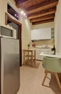 a kitchen with a refrigerator and a table with a chair at HolidHome - Soave Borgo Suite - Mini appartamento di charme nelle mura medievali in Soave