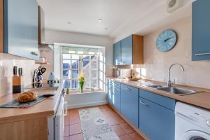 a kitchen with blue cabinets and a clock on the wall at 1 Bed in Queen Camel oc-c30506 in Queen Camel
