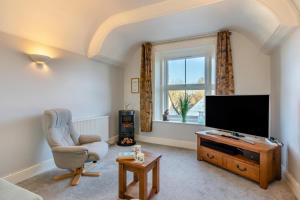 a living room with a flat screen tv and a chair at 1 Bed in Queen Camel oc-c30506 in Queen Camel