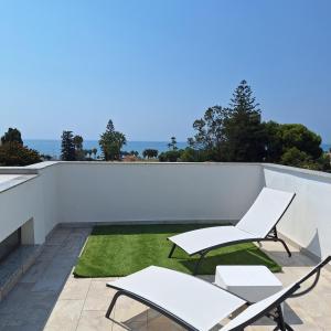 a patio with two white chairs and a lawn at Chilches Sunset Beach in Vélez-Málaga