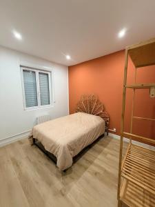 a bedroom with a bed with an orange wall at La Maison du Souvenir in Beaucourt-sur-lʼAncre