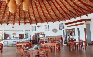a restaurant with tables and chairs and a kitchen at Dos Mundos Pacific Resort in Monterrico