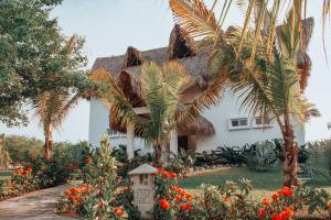 a white house with palm trees and a pathway at Dos Mundos Pacific Resort in Monterrico