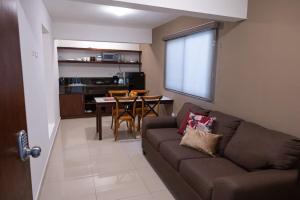 a living room with a brown couch and a kitchen at Casa Rosales in Los Mochis