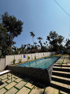 a swimming pool with a stone wall and stairs at Nellarachal Homestay in Ambalavayal