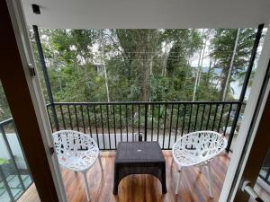 a balcony with two chairs and a table and a table at Nellarachal Homestay in Ambalavayal