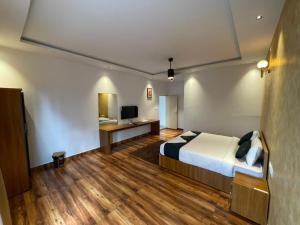 a bedroom with a bed and a desk with a television at Nellarachal Homestay in Ambalavayal